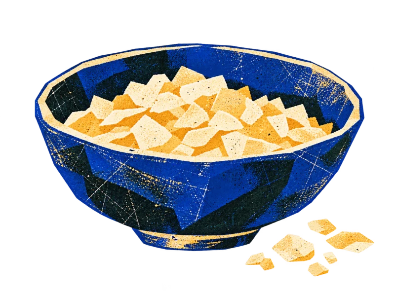 A shallow blue bowl containing a modest portion of pale manna flakes.